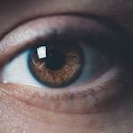 Detailed macro photo of a human eye showcasing brown iris with reflection. Perfect for medical and artistic uses.